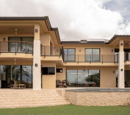 Modern two-story house with large windows and balcony.
