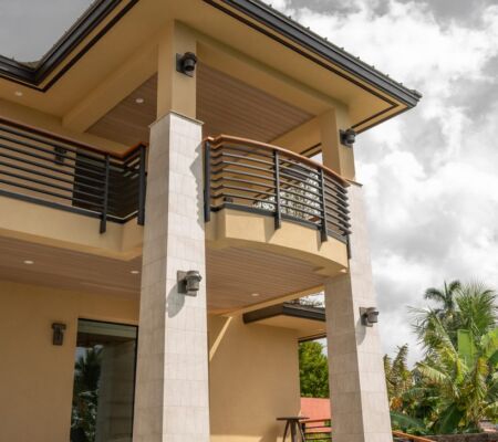 Modern two-story house with a balcony and cloudy sky.