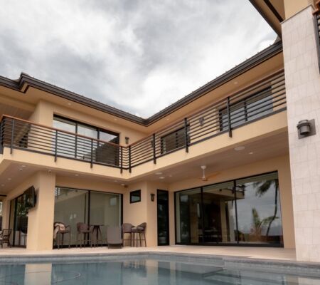 Modern house with a pool and balcony under a cloudy sky.