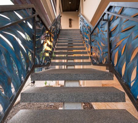 Staircase with artistic leaf-patterned railings and warm lighting.