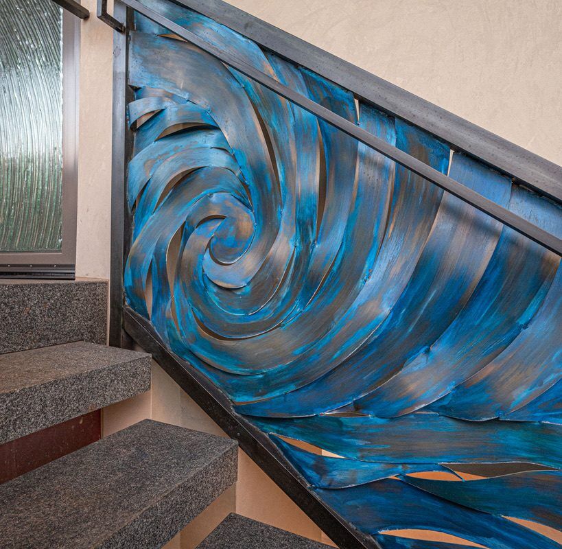 Staircase with a vibrant blue and black swirling metal railing design.