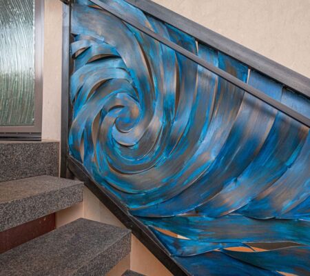 Staircase with a vibrant blue and black swirling metal railing design.