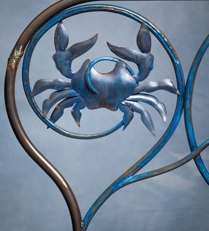 Metal crab sculpture on a blue background.