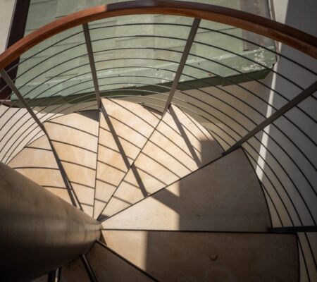 Shadow patterns on a spiral staircase with metal railings.
