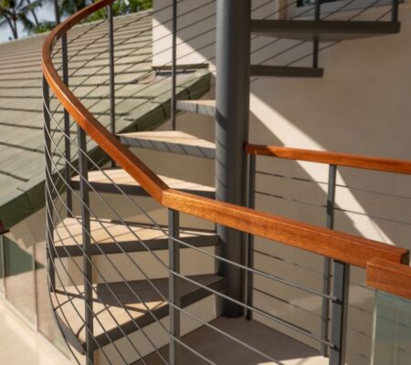 Modern staircase with wooden handrail and metal cable railing.