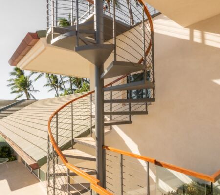 Spiral staircase with wooden handrails in a bright indoor space.