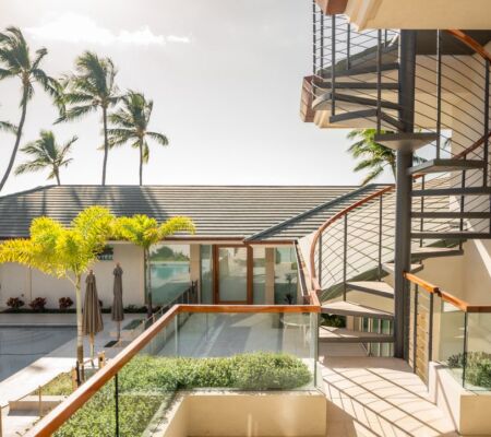 Modern balcony with spiral staircase and tropical palm trees by the beach.