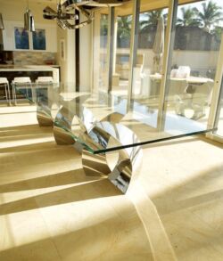 Modern glass coffee table with metal legs in a sunlit room.