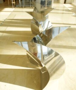 Shiny star-shaped metal sculpture casting shadows on the floor.