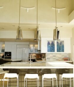 Modern kitchen with island and bar stools under pendant lights.