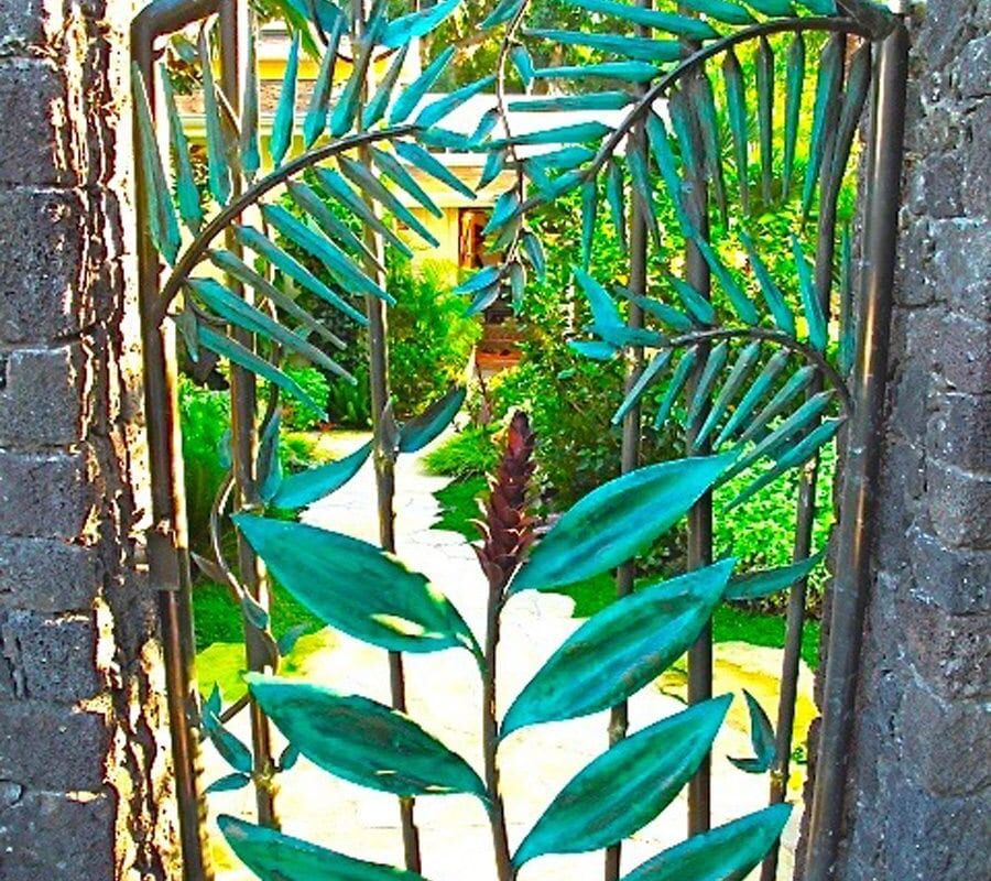 A decorative metal gate with leaf patterns in a garden.