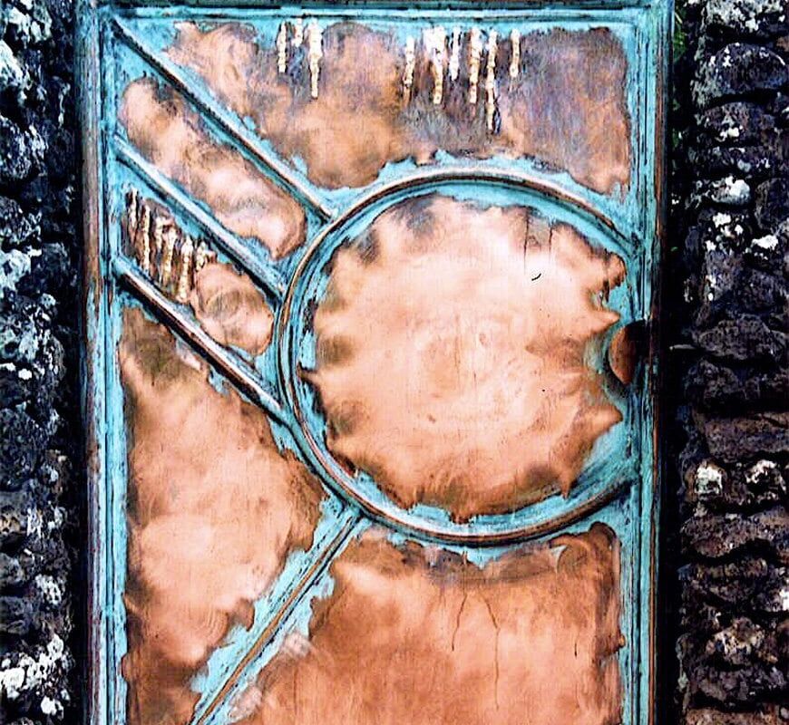Rustic metal door with geometric patterns and a large circular design.