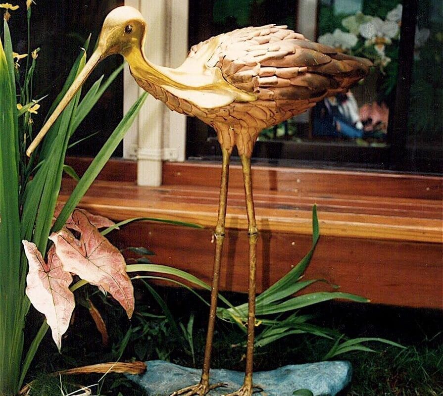 Decorative golden bird sculpture in a garden setting.