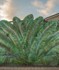 Large green sculpture resembling a fan of leaves against a cloudy sky.