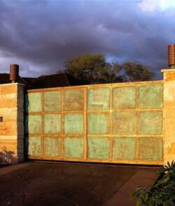 Large rusty metal gate under a cloudy sky.