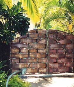 Rustic wooden gate surrounded by lush greenery and palm trees.