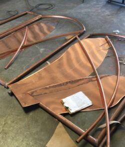 Stenciled banana leaves and round copper framework Disassembled wooden furniture parts with metal frames on the floor.