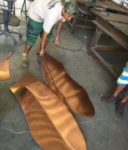 Pounding and shaping of the banana leaf texture and vein work. Two large, freshly cut wood slabs displayed on a workshop floor.