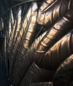 The main entry gate with the texture of the leaves with all natural copper colors. Close-up of intricately carved metallic feathers with a bronze finish.
