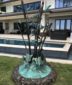Bamboo Fire Features Artistic bronze sculpture with a pool and modern house in background.