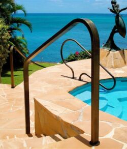 A pool handrail overlooking the ocean with a dolphin sculpture nearby.