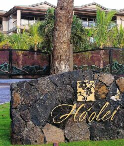 Stone sign with gold lettering reading 'Hadley' in a lush garden setting.