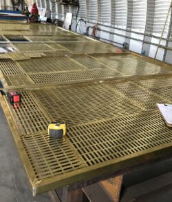 Large metal grates drying on wooden supports inside a warehouse.