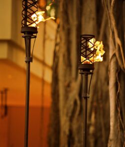 Two lit tiki torches glowing warmly against a dark backdrop.