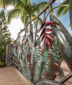 This stunning design incorporates a red heat induced color for the flower "Heliconia" and green patina solution for the foliage. Decorative metal fence with leaf and chili designs outdoors.