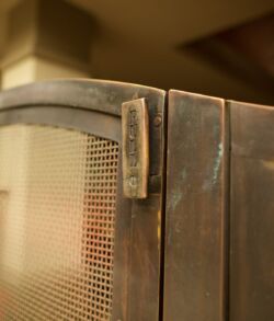 Close-up of a vintage metal cabinet door with a mesh panel and latch.