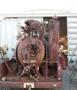 Rear view of the Sculpture of Time Rusty, old machine parts stacked on a trailer in a yard.