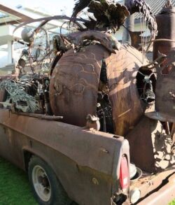 Rear view of the Sculpture of Time on display at TedXMaui Old rusted machinery loaded onto a pickup truck bed.