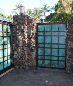 Stone and glass wall corner with metal-framed windows under clear sky.