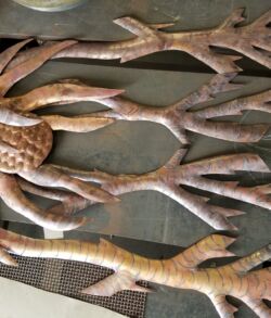 Pounded copper as the base of the Hala tree A metal wall sculpture of a tree with detailed branches and roots.