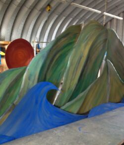 Final fabrication day Colorful, flowing sculptures resembling waves in an indoor workshop.