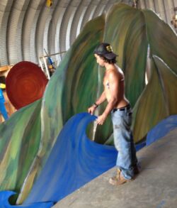 A shirtless boy with a hat plays on a colorful indoor playground slide.