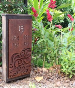 Free standing building signs A wooden door with the number 15 surrounded by lush greenery and flowers.