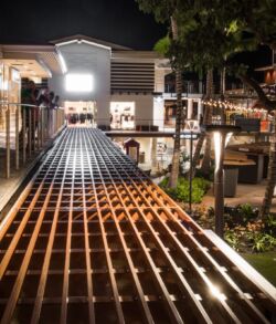 Illuminated outdoor pathway with wooden lattice and cozy seating area at night.