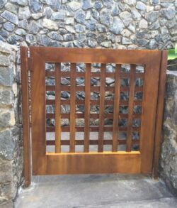 Pedestrian side walk gate Wooden gate with square lattice design against stone walls.