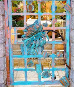 Decorative turquoise metal door with floral design.