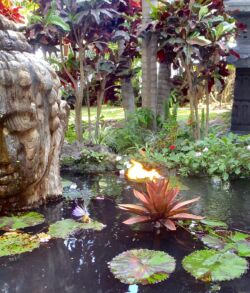 Copper Lotus fire sculpture Serene garden pond with a Buddha statue and water lilies.