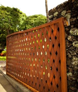 Close up side angle of Main entrance Decorative wooden fence with diamond cutouts in a garden setting.