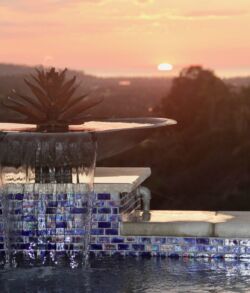 Copper lotus water bowl accenting the sunset Sunset over a tranquil pool with a fountain and mosaic tiles.