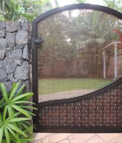 Side pedestrian gate Elegant black metal gate with a curved design in a garden.