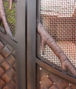 Detail close up of Hala branches, Copper weave, and screen mesh Close-up of a metal gate with woven leather details and mesh panels.