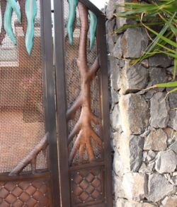 A tree branch shaped like a hand with fingers, against a stone wall.