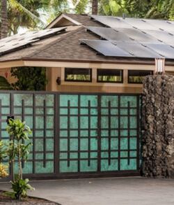 Modern house entrance with solar panels and green gate.