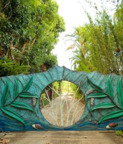 Artistic green gate with circular window and nature backdrop.
