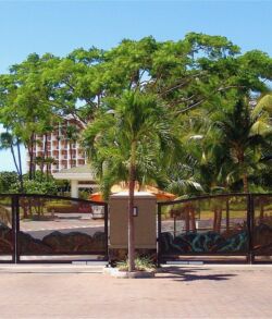 Copper and brass entry and exit gates at the Ho'olei Maui, Wailea Gated entrance with lush greenery and a building in the background.