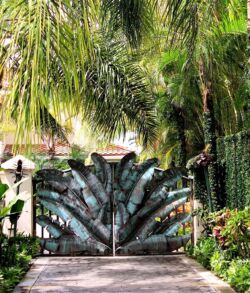 Copper banana leaf main entrance gate Intricately carved stone peacock gate surrounded by lush greenery.
